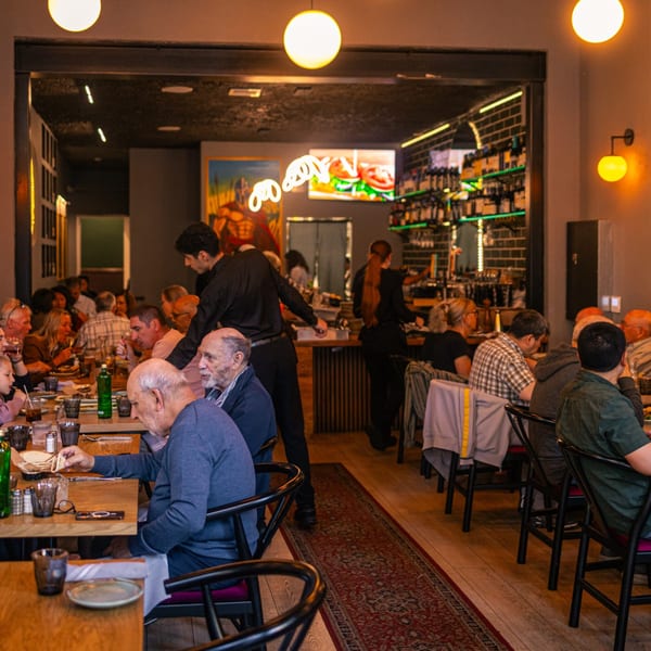 Diners enjoying meals at The Parthenon, a Greek restaurant with a lively atmosphere and attentive staff.